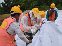 Para pekerja sedang memasang non-woven geotextile pada pembuatan jalan di daerah Sumatra Non-woven geotextile instalasai jalan Sumatra